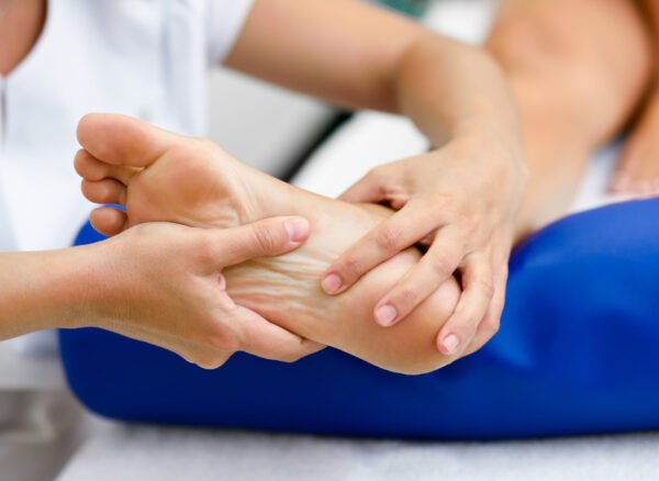 Medical massage at the foot in a physiotherapy center. Female physiotherapist inspecting her patient.