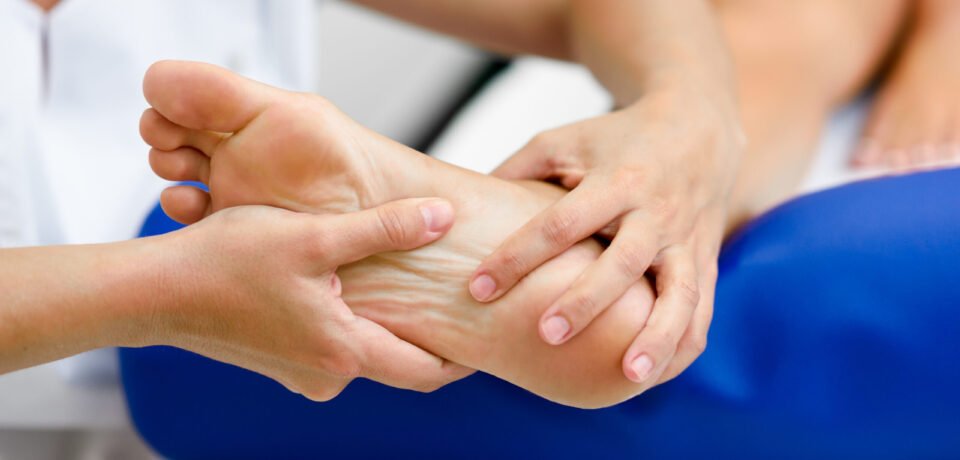 Medical massage at the foot in a physiotherapy center. Medical massage at the foot in a physiotherapy center. Female physiotherapist inspecting her patient.