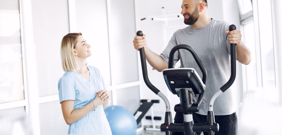 patient-doing-exercise-spin-bike-gym-with-therapist (1) Pulmonary Rehabilitation - AR Clinics Islamabad